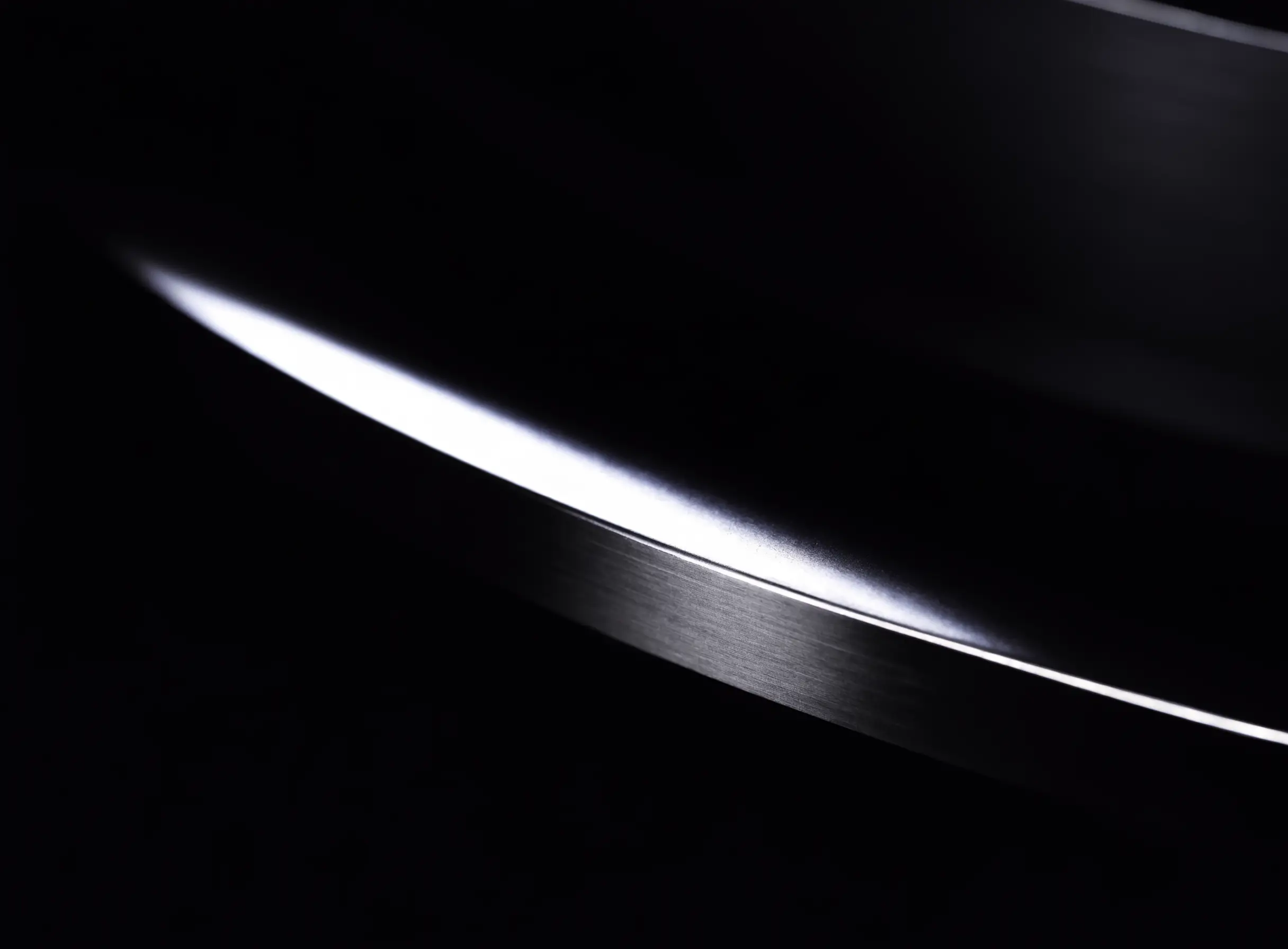 Brushed platinum surface catching a single thin sweep of cold light in the dark